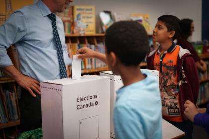 Student inserting a ballot in ballot box