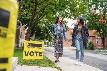 Electors walking towards a polling site following Elections Canada Vote signs that indicate the polling place.