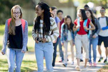 A group of students walk together in a residential neighborhood. 