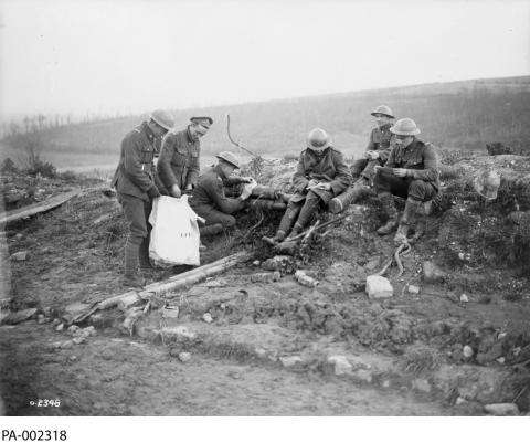 Black and white photograph of a group of soldiers in an empty battlefield marking their ballots.  