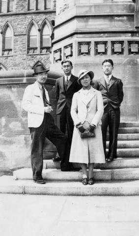  A black and white photograph of a group of four Japanese men and women, standing on the steps of Parliament.  