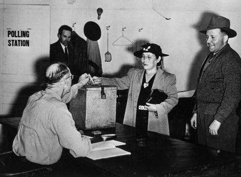 Photograph of a Japanese woman casting her ballot in a polling station.