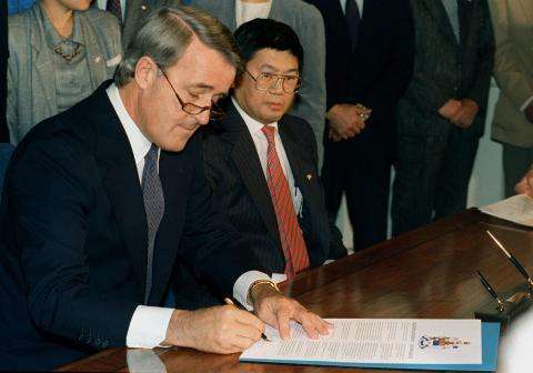  Prime Minister Brian Mulroney signs an official document. The Canadian government formally apologizes to Japanese Canadians for denying them their civil and democratic rights.