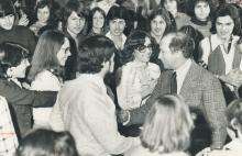 CE08-Youth-L Black and white photograph of Prime Minister Pierre Trudeau shaking hands with a young person, while standing at the centre of a large group of smiling youth.